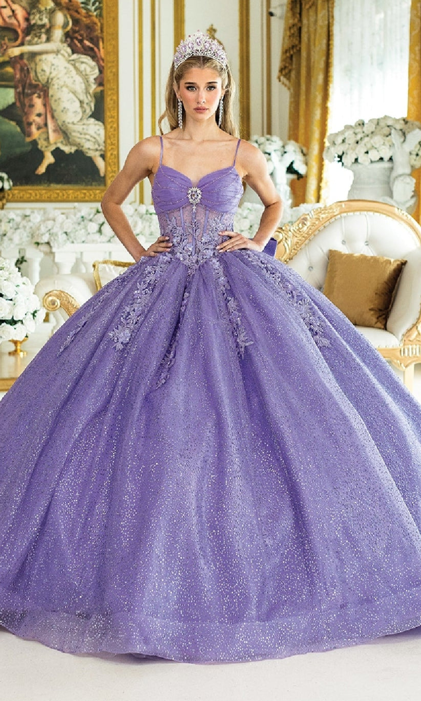 A young woman stands indoors wearing the Dancing Queen 1958 Long Quinceañera Dress with Bow and a tiara, surrounded by white and gold furniture and floral arrangements.